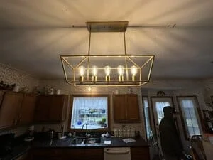 Modern pendant light fixture with glass panels and metal frame installed above kitchen island