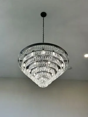 Multi-tiered crystal chandelier with black metal frame and chain suspension installed on ceiling