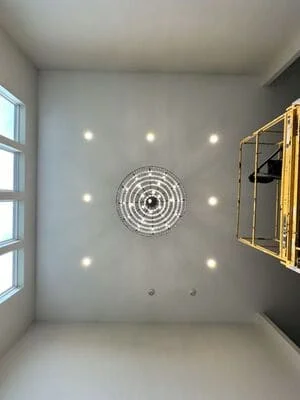 Recessed lighting installation with nine fixtures surrounding decorative clock on gray accent wall