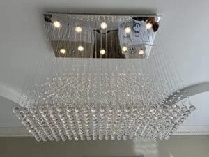 Crystal chandelier with LED lights and rectangular metal frame mounted on ceiling
