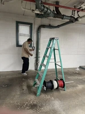 Electrician installing black electrical conduit in commercial ceiling and wall systems