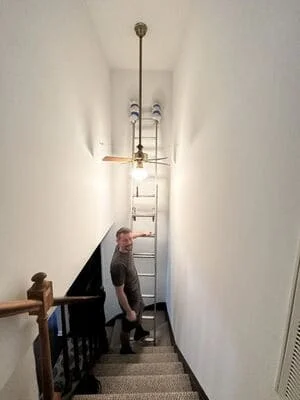 Pendant light fixture installed in narrow hallway with metal and glass elements