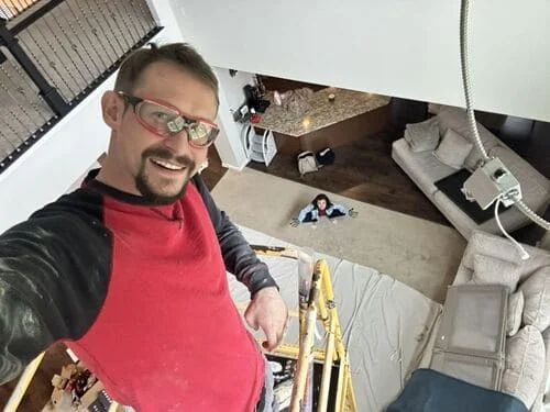 Electrician installing conduit and wiring in residential ceiling cavity