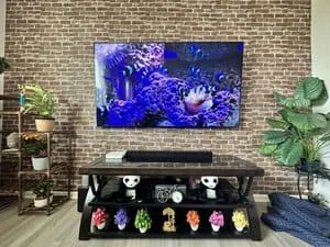 Mounted flat-screen TV on brick wall with concealed wiring and black media console below