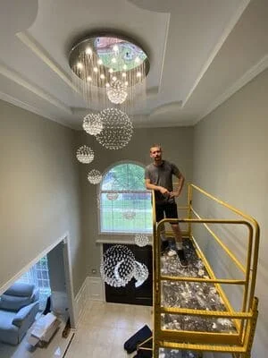Multi-level pendant lights with spherical shades installed in two-story foyer with recessed ceiling lighting