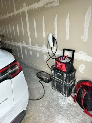 EV charger installation in garage with red charging equipment and wall-mounted electrical components