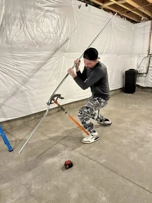 Electrician installing electrical conduit and wiring with protective plastic sheeting in interior space