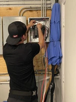 Electrician installing copper wiring and conduit in residential electrical panel