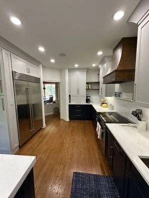 Recessed ceiling lights in white kitchen with white cabinets and dark lower cabinetry