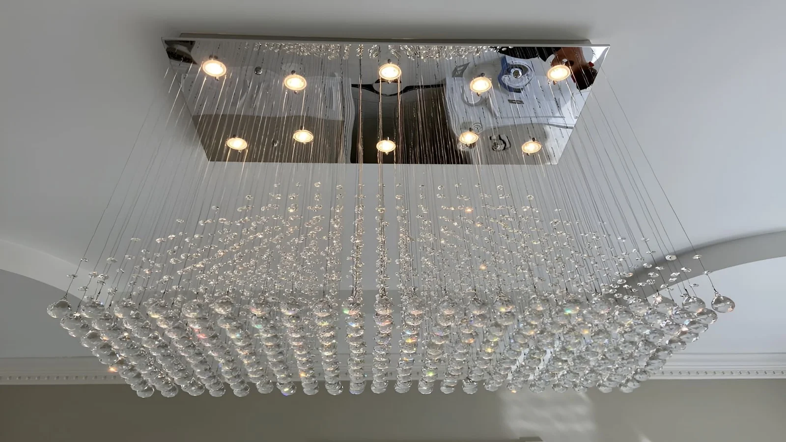Crystal chandelier with hanging glass elements and integrated recessed LED lights in ceiling fixture