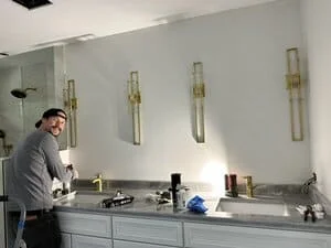 Four brass pendant lights with glass shades installed above bathroom vanity