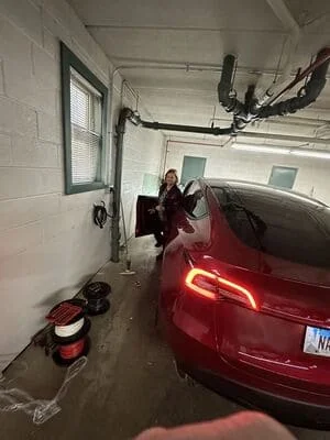 Garage interior with overhead electrical conduit, wiring, and outlets installed above parked vehicle