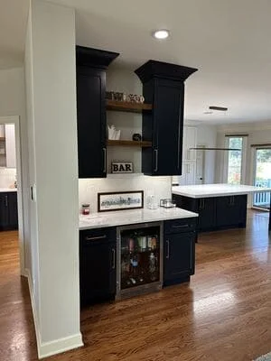 Black kitchen bar cabinetry with recessed ceiling lights and glass-front cooler